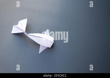 Origami de poisson en papier blanc isolé sur un fond gris vierge. Origami de poisson en papier blanc isolé sur un fond gris Banque D'Images