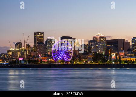 Vieux-Port de Montréal et horizon du centre-ville la nuit. Les lumières colorées des bâtiments se reflètent dans l'eau. Montréal, Québec, Canada. Grande roue. Banque D'Images