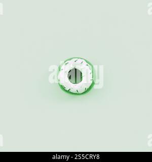 Un seul petit beignet en plastique repose sur un fond coloré pastel. Composition minimale de pose à plat. Vue de dessus. Un seul petit beignet en plastique repose sur un pastel Banque D'Images