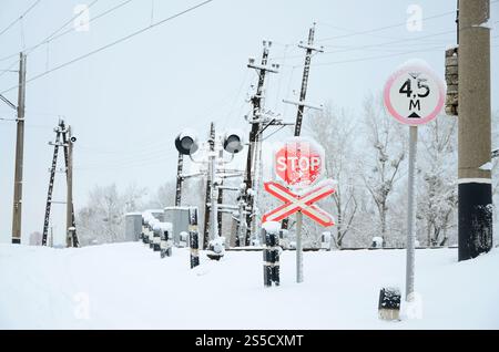 Arrêter. Le panneau rouge est situé sur l'autoroute qui traverse la ligne de chemin de fer en hiver Banque D'Images