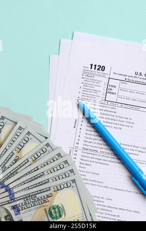 1120 formulaire d'impôt se trouve près de cent billets de dollars et stylo bleu sur un fond bleu clair. Déclaration de revenus des sociétés AMÉRICAINES. 1120 formulaire d'impôt se trouve près Banque D'Images