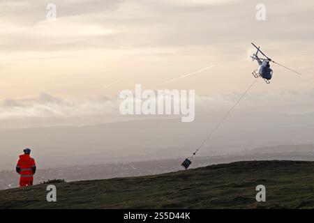Arthur's Seat Édimbourg, Écosse, Royaume-Uni. 14 janvier 2025. Un hélicoptère effectuant plusieurs voyages pour livrer du matériel en préparation pour réparer le chemin en zig zag qui mène du parc Holyrood jusqu'à juste en dessous du sommet du lieu touristique populaire, le nombre enrmous de visiteurs au parc Holyrood provoque une érosion constante des chemins du parc. Pour des raisons de sécurité, la High Road et le trottoir seront partiellement fermés du 14 au 17 janvier 2025 0800 au 1600. Credit : Arch White/Alamy Live news Banque D'Images