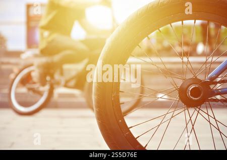 Une roue de vélo BMX dans le contexte d'une rue avec des coureurs cyclistes brouillée. Extreme Sports Concept Banque D'Images