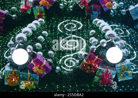 Un fragment d'un immense arbre de Noël avec de nombreux cadeaux, décorations et lumineux des lampes. Photo d'un arbre de Noël décoré close-up Banque D'Images