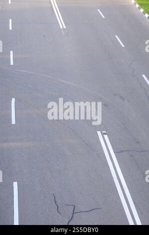 Mauvaise route asphaltée endommagée avec nids de poule. Réparation de plaques d'asphalte. Mauvais asphalte dangereux route automobile cassée, fissures et nids de poule dans l'asphalte. Banque D'Images