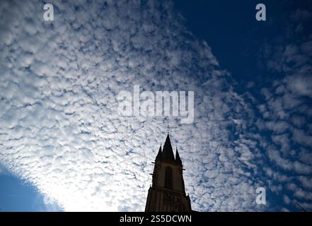 Viernheim, Allemagne. 14 janvier 2025. Les nuages dérivent au-dessus de la tour de l'église de l'apôtre catholique par temps froid et ensoleillé. Crédit : Arne Dedert/dpa/Alamy Live News Banque D'Images