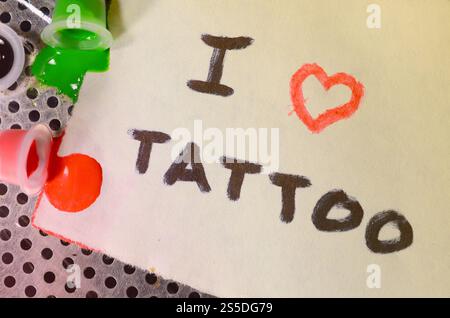 J'adore le tatouage. Le texte est écrit sur une petite feuille de papier à côté des capuchons rentournés avec de l'encre tattoo colorée Banque D'Images