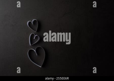 Papier blanc en forme de coeur dans l'ombre sur fond noir Banque D'Images