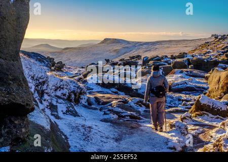 Femme marcheuse sur le bord sud de Kinder Scout dans le Peak District avec un saupoudrage de neige Banque D'Images