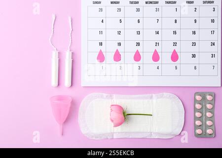 Composition de pose plate avec calendrier et produits menstruels sur fond violet Banque D'Images