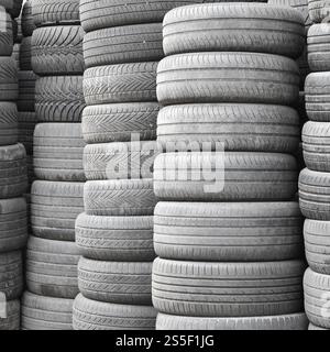 Vieux pneus usagés empilés avec des piles élevées dans le garage secondaire de magasin de pièces de voiture de près. Vieux pneus usagés empilés avec des piles élevées dans des pièces de voiture secondaires Banque D'Images