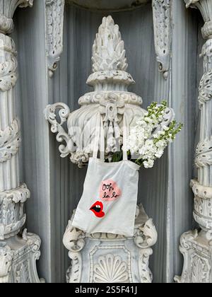 Cette photo juxtapose un sac fourre-tout en toile contemporain, orné de graphismes ludiques et rempli de fleurs blanches fraîches, contre le marbre complexe Banque D'Images