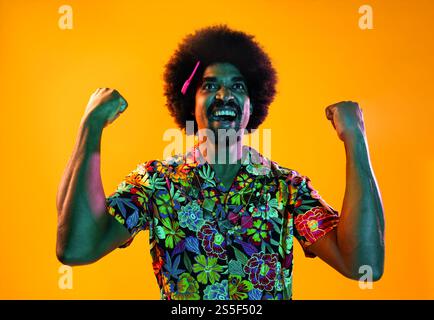 Portrait d'homme africain en studio sur fond coloré - cool noir jeune homme avec tenue élégante posant, éclairage coloré créatif Banque D'Images