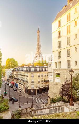 Vue sur la rue parisienne au crépuscule avec la Tour Eiffel en arrière-plan et un ciel bleu clair, Paris, France Banque D'Images