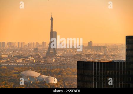 Lever de soleil sur Paris avec une vue brumeuse sur la Tour Eiffel et les bâtiments modernes de Louis Vuitton au premier plan, France Banque D'Images