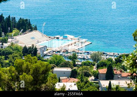 Vue aérienne d'une piscine olympique extérieure, bateaux amarrés dans une petite marina, entouré d'une végétation luxuriante à Split, Croatie Banque D'Images