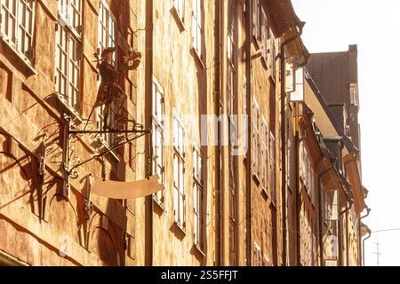 La lumière chaude du soleil illumine un signe pittoresque de magasin d'antiquités sur un bâtiment rustique avec des fenêtres étroites dans une rue calme dans la vieille ville de Gamla Stan, Stockholm, Suède Banque D'Images