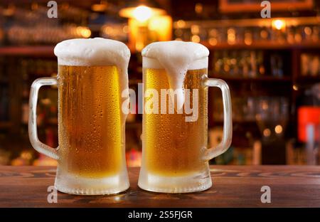 Tasses froides de bière dans un bar sur le comptoir en bois Banque D'Images