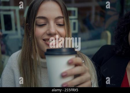 Une femme souriante tenant une tasse de café, dégustant une boisson chaude, Berlin, Allemagne Banque D'Images