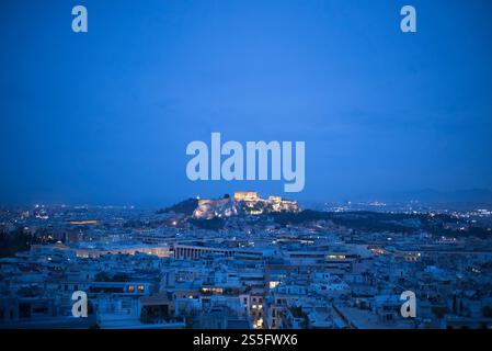Une vue en soirée d'un paysage urbain après le coucher du soleil avec des ruines antiques illuminées sur une colline, Acropole, Athènes, Grèce Banque D'Images