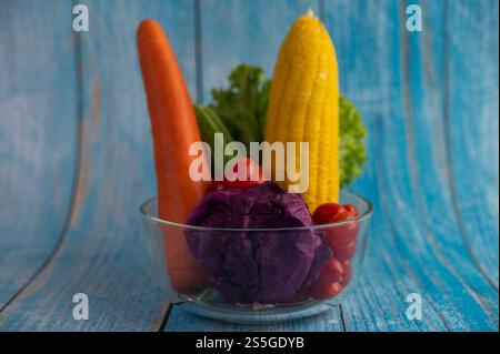 Tomates, carottes, concombres, oignons, salades, oignons et chou violet dans une tasse en verre. Mise au point sélective Banque D'Images