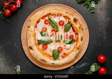 Pizza Margherita avec basilic frais, mozzarella et tomates cerises sur une assiette en bois rustique Banque D'Images