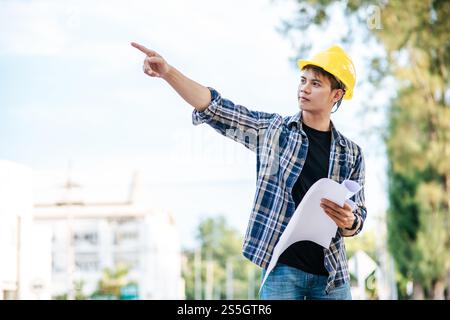 Les architectes tiennent le plan de construction et vérifient le travail. Banque D'Images