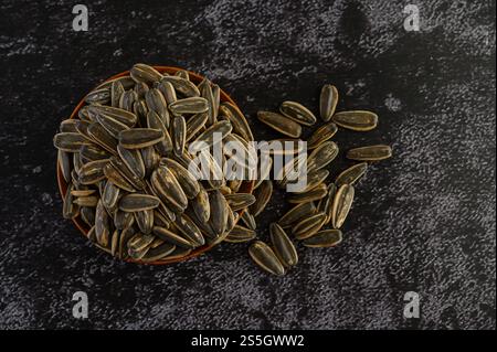 Graine de fleur de soleil dans un bol en bois sur le sol en ciment noir. Vue de dessus. Banque D'Images