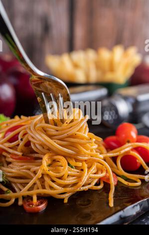 Spaghetti dans une tasse noire avec tomates et laitue. Mise au point sélective. Banque D'Images