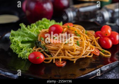 Spaghetti dans une tasse noire avec tomates et laitue. Mise au point sélective. Banque D'Images