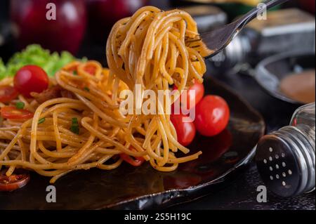 Spaghetti dans une tasse noire avec tomates et laitue. Mise au point sélective. Banque D'Images