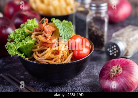 Spaghetti dans une tasse noire avec tomates et laitue. Mise au point sélective. Banque D'Images