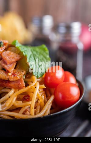 Spaghetti dans une tasse noire avec tomates et laitue. Mise au point sélective. Banque D'Images