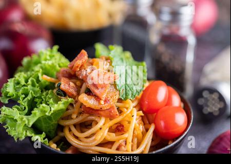 Spaghetti dans une tasse noire avec tomates et laitue. Mise au point sélective. Banque D'Images