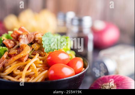 Spaghetti dans une tasse noire avec tomates et laitue. Mise au point sélective. Banque D'Images