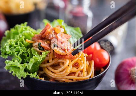 Spaghetti dans une tasse noire avec tomates et laitue. Mise au point sélective. Banque D'Images