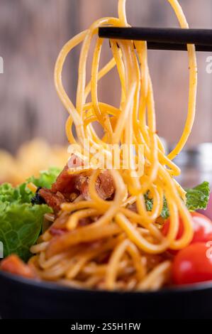 Spaghetti dans une tasse noire avec tomates et laitue. Mise au point sélective. Banque D'Images
