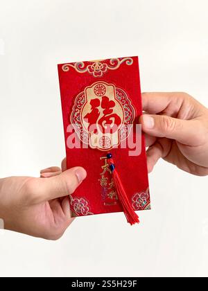 Deux mains donnant des enveloppes rouges chinoises, également connues sous le nom de hongbao ou angpao. Il est rempli d'argent, et célèbre pour le nouvel an chinois ou le nouvel an lunaire. Banque D'Images