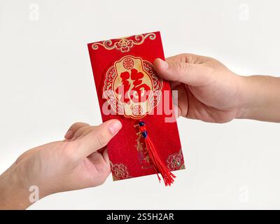 Deux mains donnant des enveloppes rouges chinoises, également connues sous le nom de hongbao ou angpao. Il est rempli d'argent, et célèbre pour le nouvel an chinois ou le nouvel an lunaire. Banque D'Images