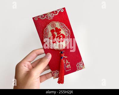 Main tenant des enveloppes rouges chinoises, également connu sous le nom de hongbao ou angpao. Ceci est souvent rempli d'argent, et célèbre pour le nouvel an chinois ou le nouvel an lunaire Banque D'Images