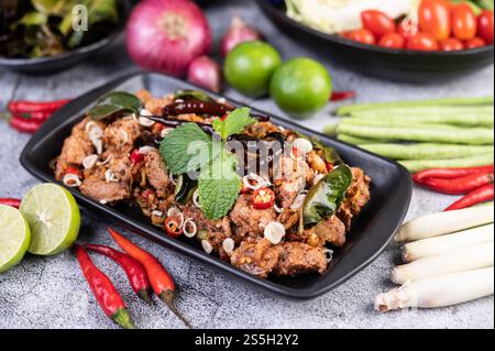 Côtelettes de porc épicées sur une assiette noire composée de citrons Chili et de plats d'accompagnement. Mise au point sélective. Banque D'Images