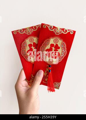 Main tenant des enveloppes rouges chinoises, également connu sous le nom de hongbao ou angpao. Ceci est souvent rempli d'argent, et célèbre pour le nouvel an chinois ou le nouvel an lunaire Banque D'Images