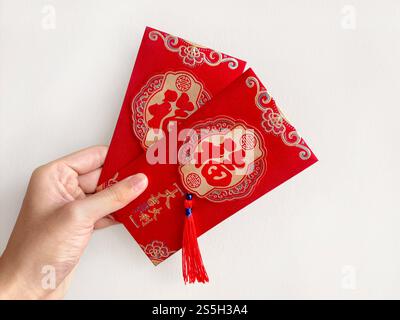 Main tenant des enveloppes rouges chinoises, également connu sous le nom de hongbao ou angpao. Ceci est souvent rempli d'argent, et célèbre pour le nouvel an chinois ou le nouvel an lunaire Banque D'Images
