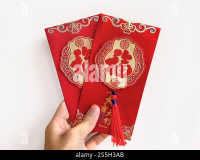 Main tenant des enveloppes rouges chinoises, également connu sous le nom de hongbao ou angpao. Rempli d'argent, et célèbre pour le nouvel an chinois ou le nouvel an lunaire. Banque D'Images