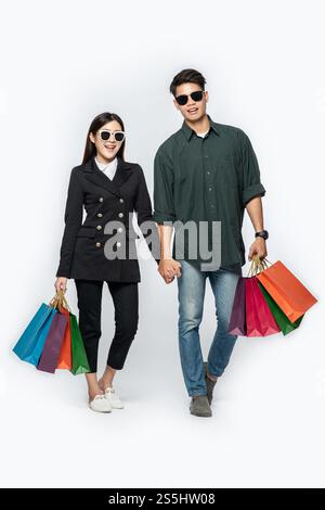 Une paire d'hommes et de femmes portaient des lunettes et transportaient beaucoup de sacs en papier pour faire du shopping. Banque D'Images