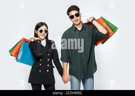 Une paire d'hommes et de femmes portaient des lunettes et transportaient beaucoup de sacs en papier pour faire du shopping. Banque D'Images