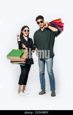 Une paire d'hommes et de femmes portaient des lunettes et transportaient beaucoup de sacs en papier pour faire du shopping. Banque D'Images