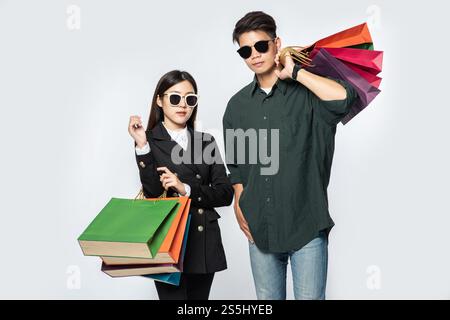 Une paire d'hommes et de femmes portaient des lunettes et transportaient beaucoup de sacs en papier pour faire du shopping. Banque D'Images