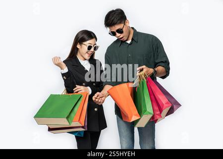 Une paire d'hommes et de femmes portaient des lunettes et transportaient beaucoup de sacs en papier pour faire du shopping. Banque D'Images