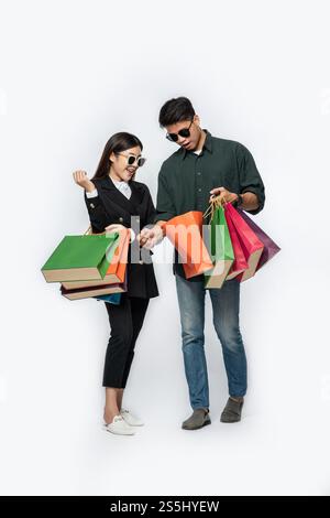 Une paire d'hommes et de femmes portaient des lunettes et transportaient beaucoup de sacs en papier pour faire du shopping. Banque D'Images